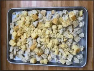 Cubed bread and cornbread mix on a baking sheet, ideal for stuffing preparation.